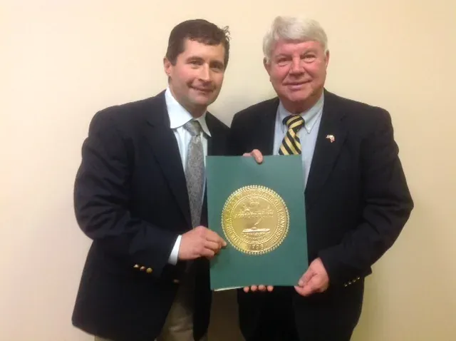 Wade Norris and Representative Jimmy Eldridge holding a framed Tennessee state resolution